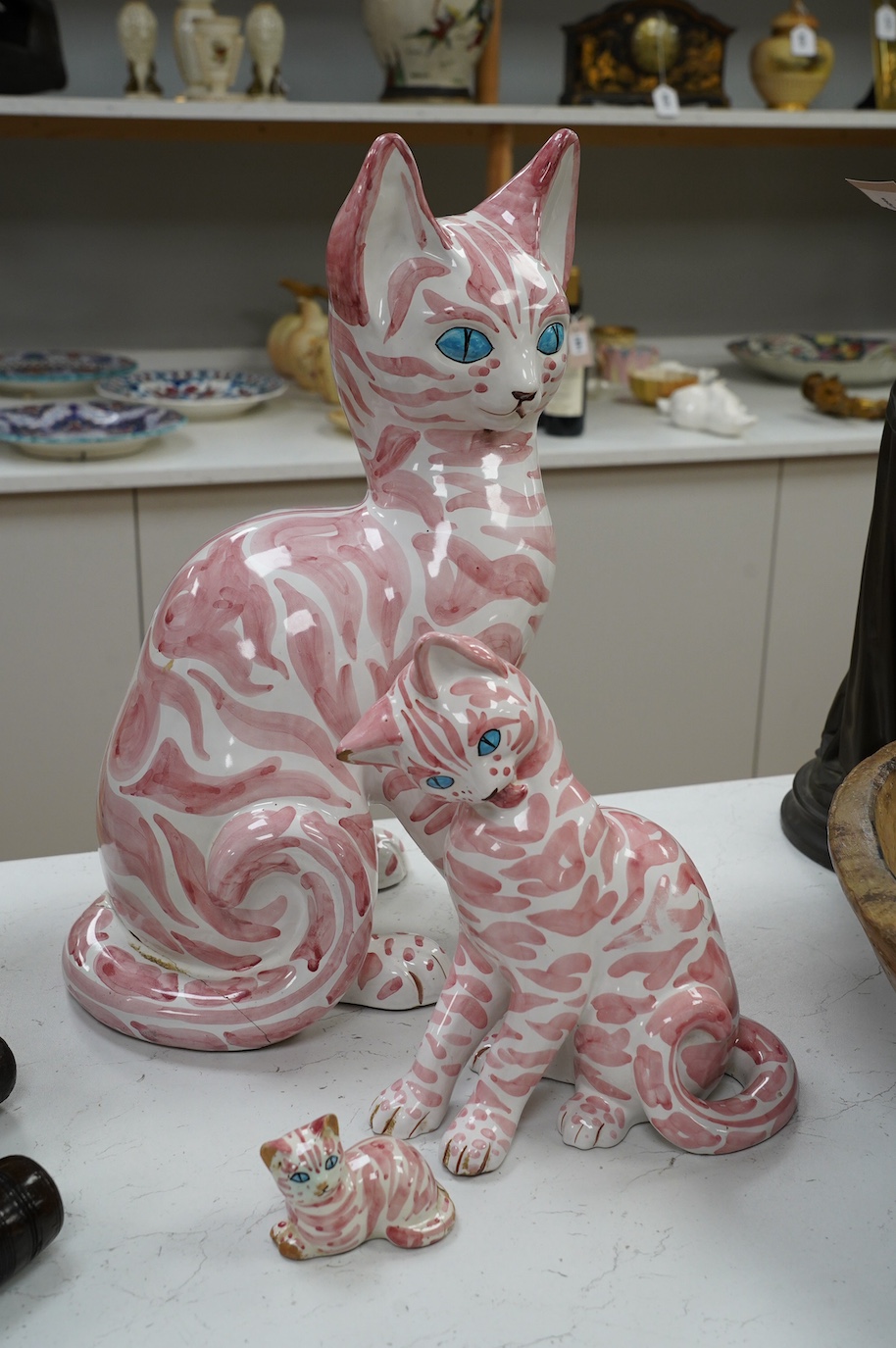 A large 1950's Italian pink maiolica seated cat and two smaller, largest 45cm. Condition - poor